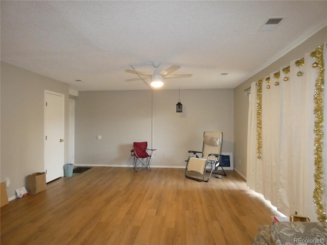 unfurnished room with a ceiling fan, baseboards, visible vents, a textured ceiling, and light wood-type flooring