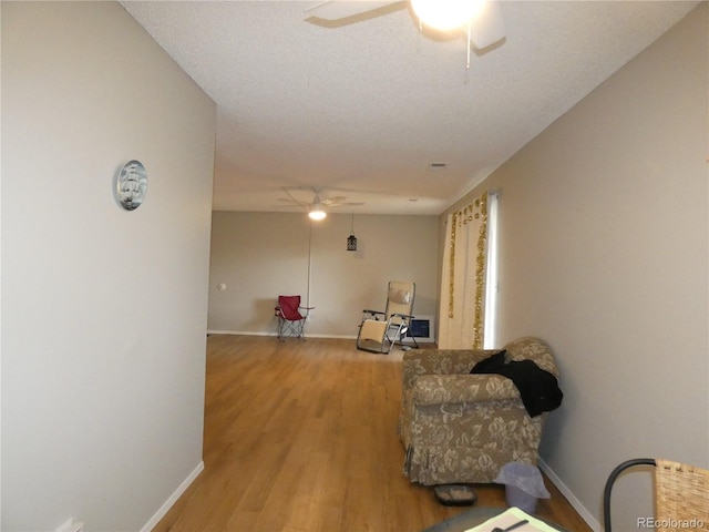 living area featuring a ceiling fan, light wood-style floors, and baseboards