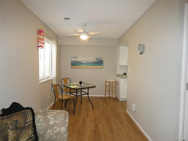 dining area featuring baseboards, light wood finished floors, and ceiling fan