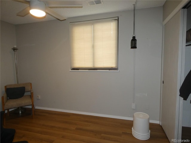 living area featuring visible vents, a ceiling fan, baseboards, and wood finished floors