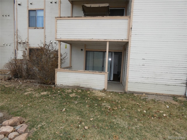 view of exterior entry with a yard and a balcony