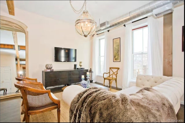 bedroom with baseboards, wood finished floors, visible vents, and a notable chandelier