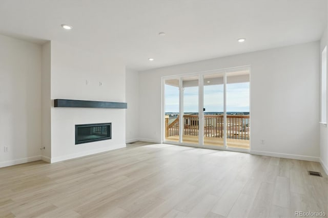 unfurnished living room featuring a water view and light wood-type flooring