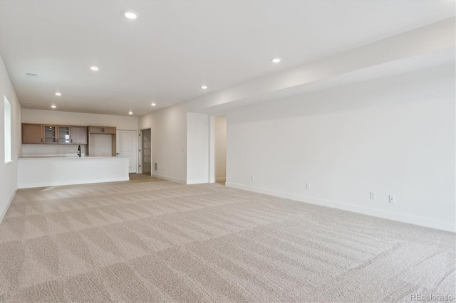 unfurnished living room featuring sink and light colored carpet