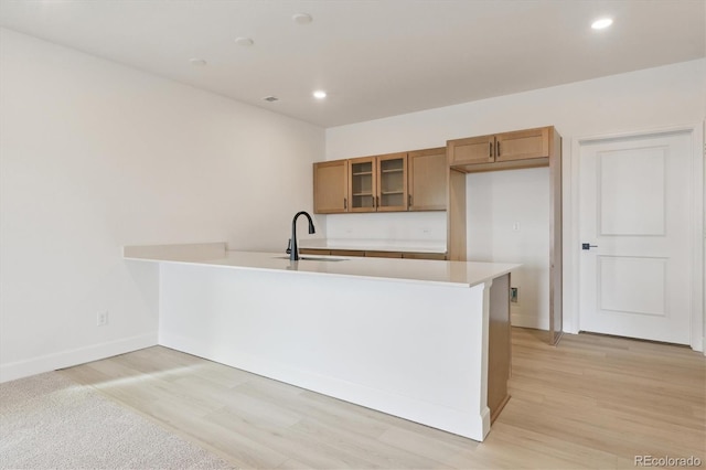 kitchen featuring sink, light hardwood / wood-style flooring, and kitchen peninsula