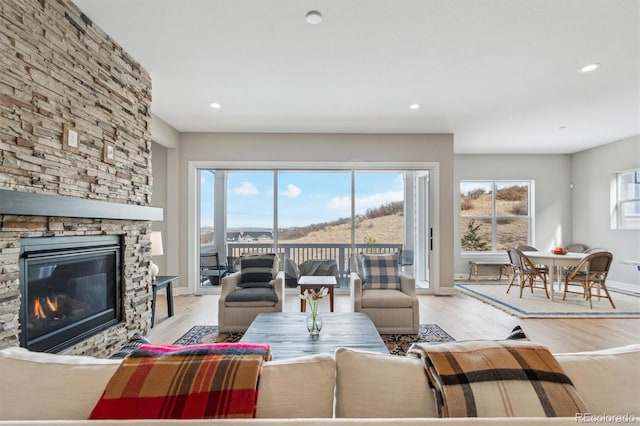 living room featuring baseboards, wood finished floors, a fireplace, and recessed lighting