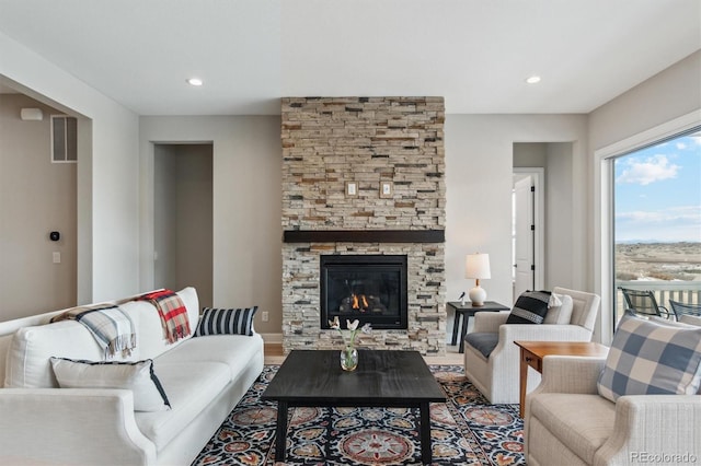 living area featuring recessed lighting, a fireplace, visible vents, and wood finished floors