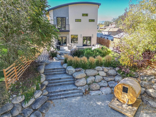 back of house with a balcony, fence, a patio, and stucco siding