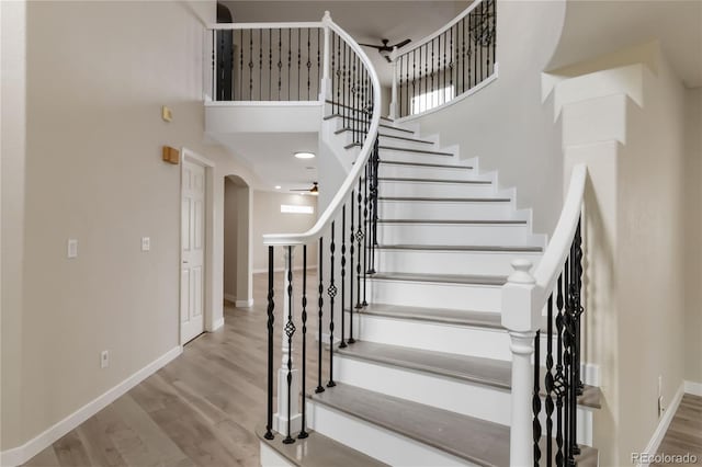9169 Fox Fire Way, Highlands Ranch, CO 80129 - staircase featuring arched walkways, wood finished floors, a high ceiling, baseboards, and a ceiling fan