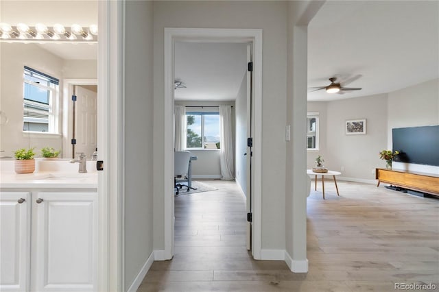 9169 Fox Fire Way, Highlands Ranch, CO 80129 - hall with light wood finished floors, a sink, and baseboards