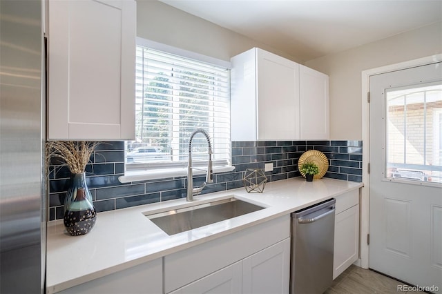 kitchen featuring a sink, stainless steel appliances, light countertops, white cabinets, and tasteful backsplash