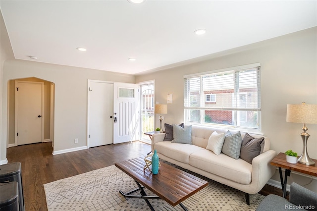 living room featuring recessed lighting, wood finished floors, arched walkways, and baseboards