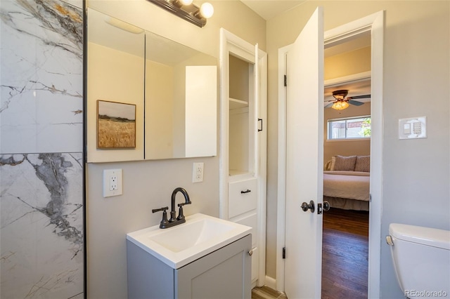 ensuite bathroom featuring vanity, wood finished floors, a ceiling fan, toilet, and connected bathroom