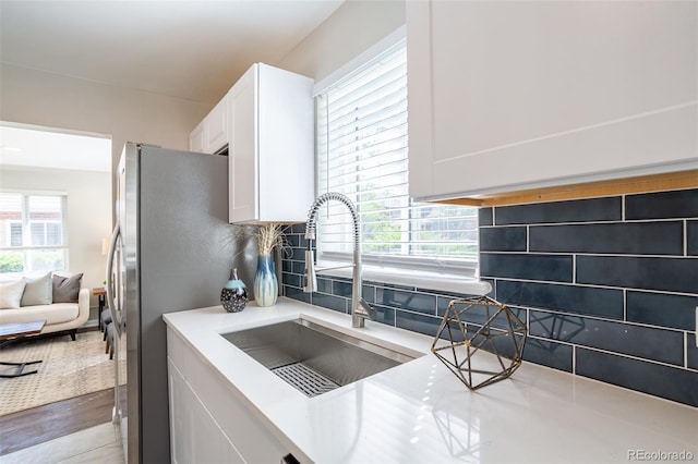 kitchen featuring a sink, light countertops, white cabinets, tasteful backsplash, and a wealth of natural light