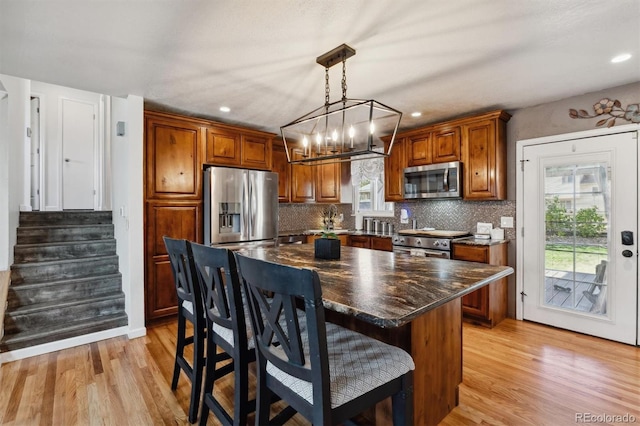 kitchen featuring decorative backsplash, a center island, stainless steel appliances, and light hardwood / wood-style flooring