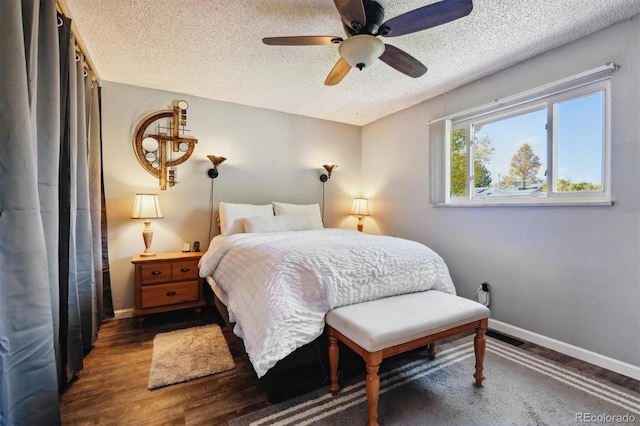 bedroom with ceiling fan, dark wood-type flooring, and a textured ceiling