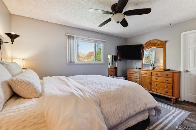 bedroom with ceiling fan, dark wood-type flooring, and a textured ceiling