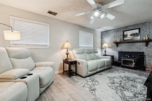 living room with a textured ceiling, light wood-type flooring, and ceiling fan