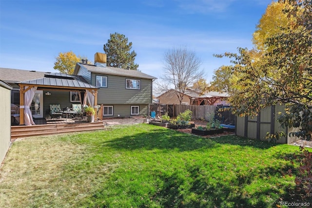 rear view of property with a gazebo, a wooden deck, and a yard