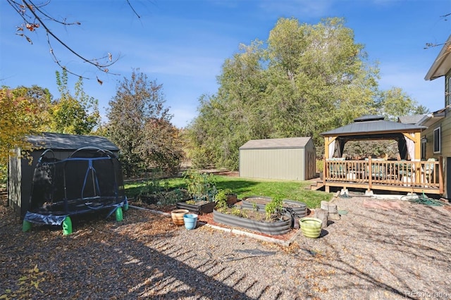 view of yard featuring a gazebo, a trampoline, a shed, and a deck