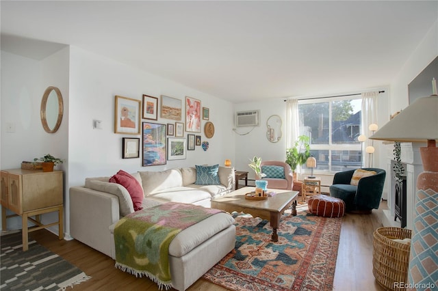 living area featuring a baseboard heating unit, an AC wall unit, and wood finished floors