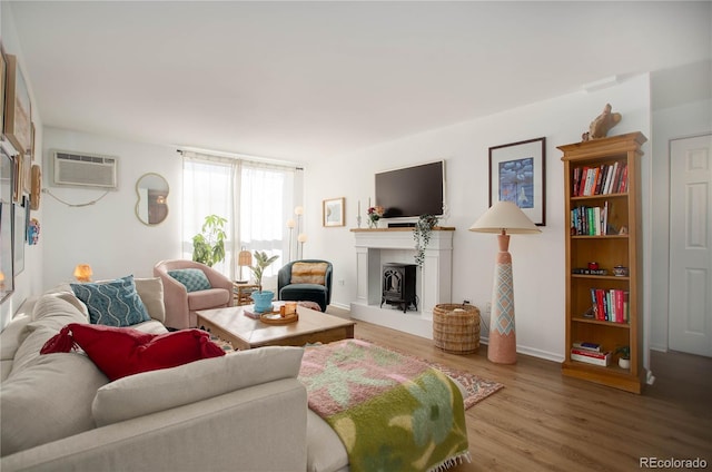 living room with an AC wall unit, hardwood / wood-style floors, and a wood stove