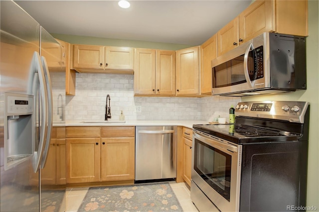 kitchen featuring appliances with stainless steel finishes, a sink, light brown cabinetry, and light countertops