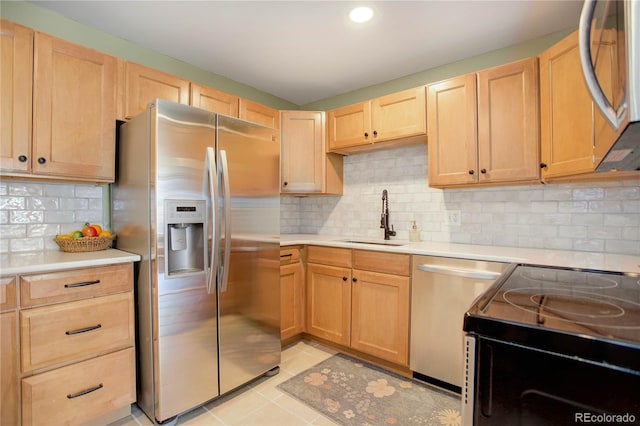 kitchen with stainless steel appliances, tasteful backsplash, sink, light tile patterned flooring, and light brown cabinetry