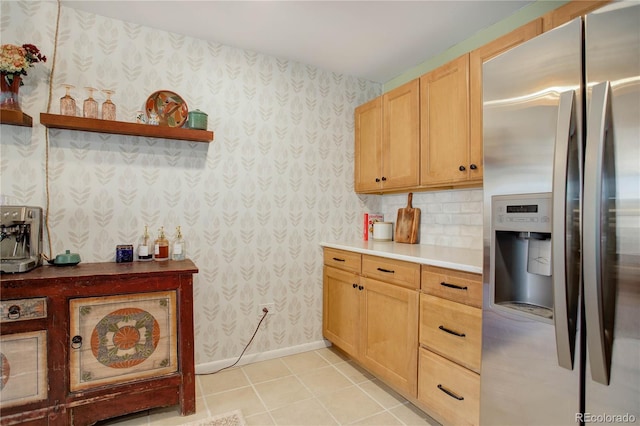 kitchen featuring wallpapered walls, light tile patterned flooring, baseboards, and stainless steel refrigerator with ice dispenser