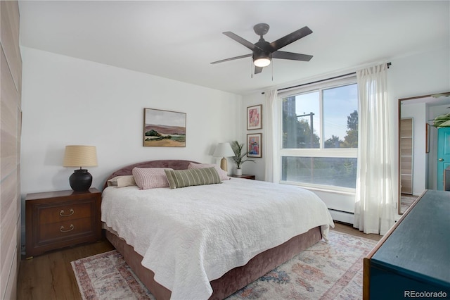 bedroom with a ceiling fan, wood finished floors, and a baseboard radiator