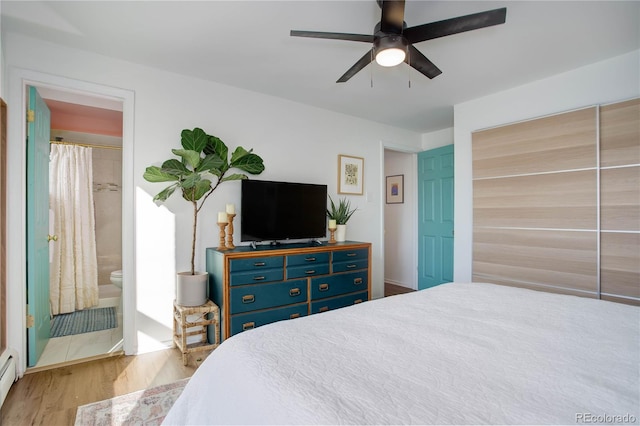 bedroom with a baseboard heating unit, connected bathroom, wood finished floors, and ceiling fan