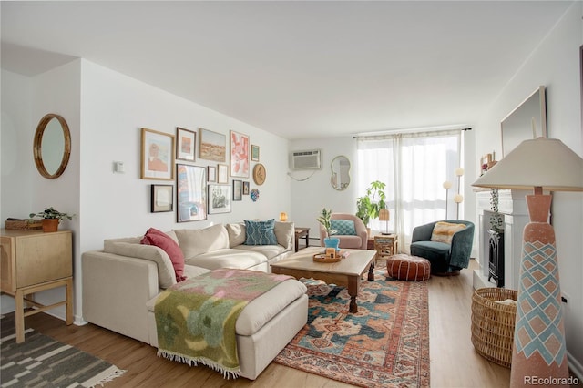 living room with a wall mounted air conditioner, a baseboard radiator, wood finished floors, and a fireplace