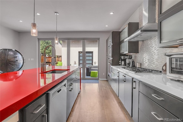 4156 Vrain St, Denver, CO 80212 - kitchen with wall chimney range hood, appliances with stainless steel finishes, light wood-style flooring, decorative backsplash, and hanging light fixtures
