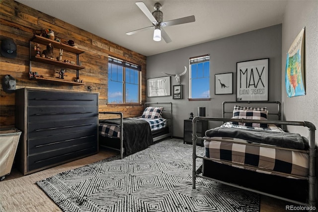 bedroom featuring wooden walls and a ceiling fan