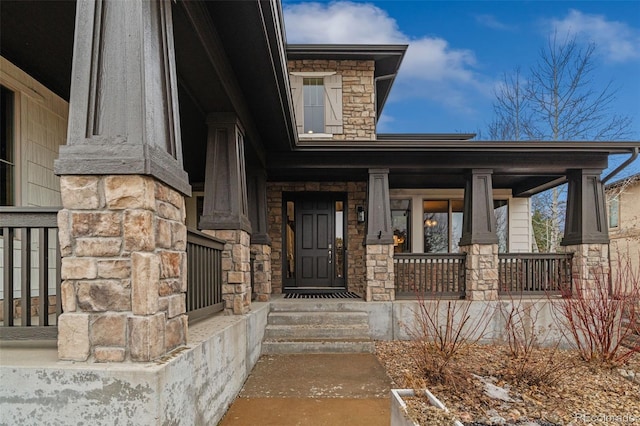 doorway to property with a porch and stone siding