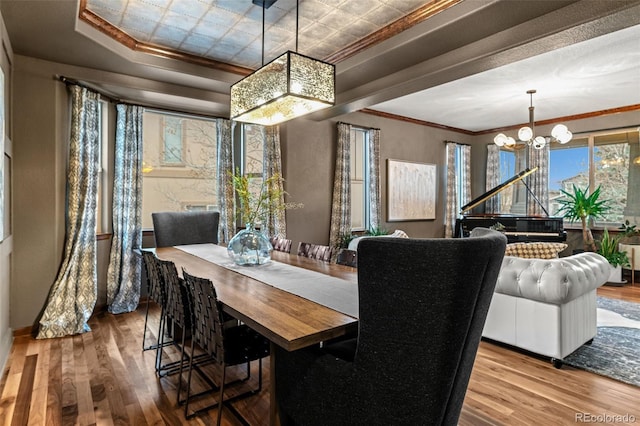 dining room with wood finished floors, a chandelier, crown molding, and baseboards