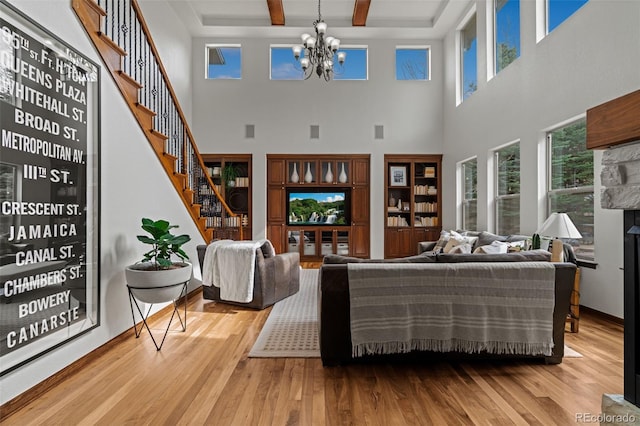 living area featuring a chandelier, stairway, wood finished floors, a high ceiling, and beam ceiling