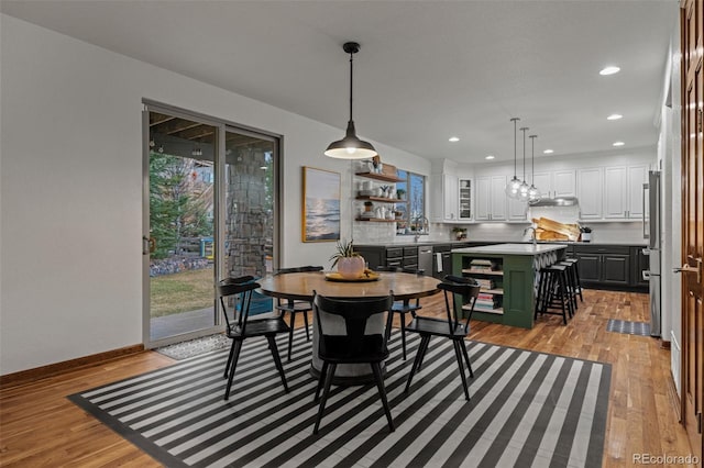 dining space with light wood-type flooring, recessed lighting, and baseboards