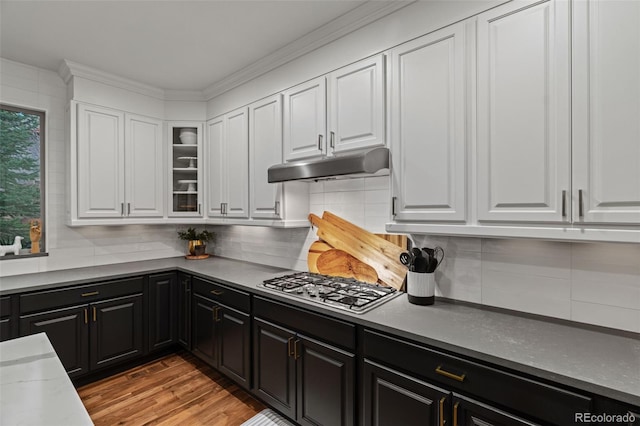 kitchen featuring under cabinet range hood, stainless steel gas stovetop, white cabinetry, dark cabinets, and crown molding
