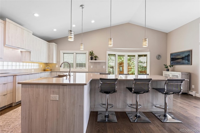 kitchen featuring modern cabinets, a sink, light brown cabinetry, vaulted ceiling, and light countertops