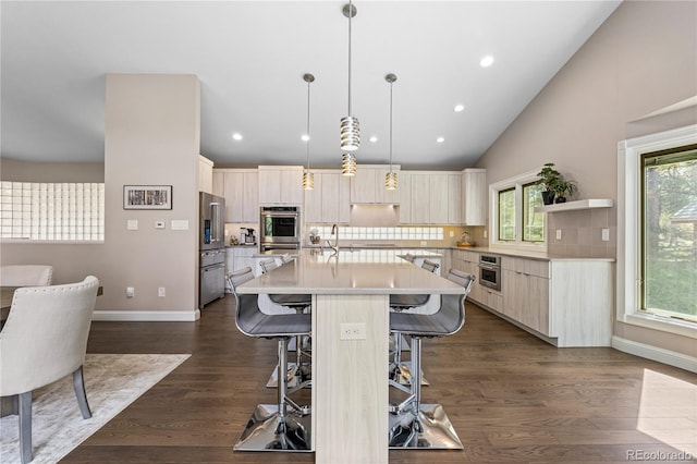 kitchen with a breakfast bar, light countertops, tasteful backsplash, stainless steel appliances, and an island with sink