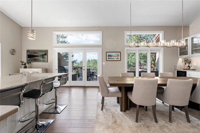 dining space with hardwood / wood-style floors, plenty of natural light, a high ceiling, french doors, and a chandelier