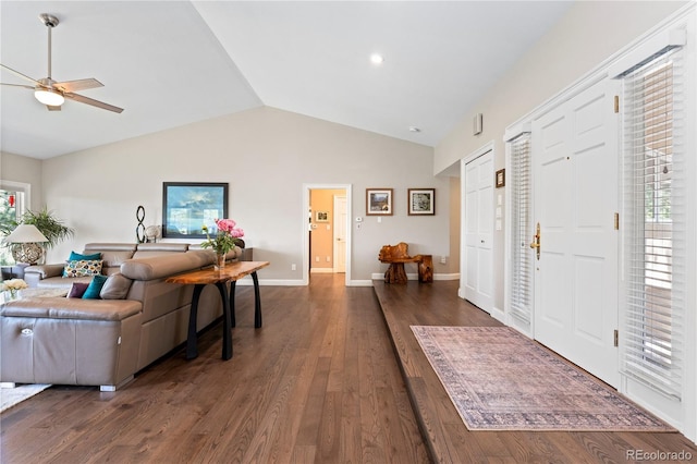 foyer with lofted ceiling, ceiling fan, dark wood-style flooring, and baseboards