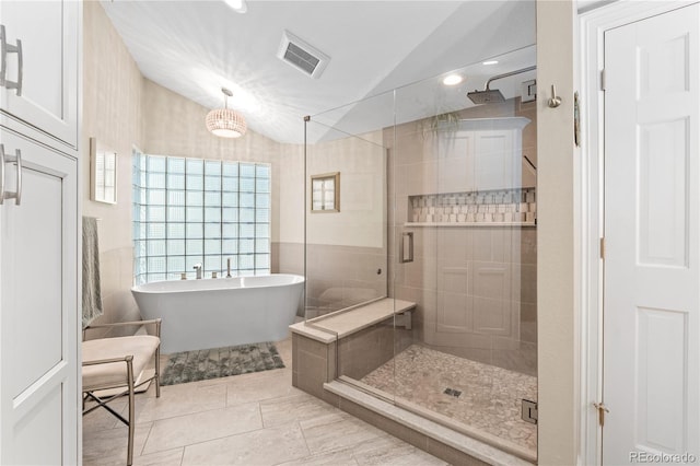 bathroom featuring a shower stall, vaulted ceiling, a soaking tub, and tile patterned floors