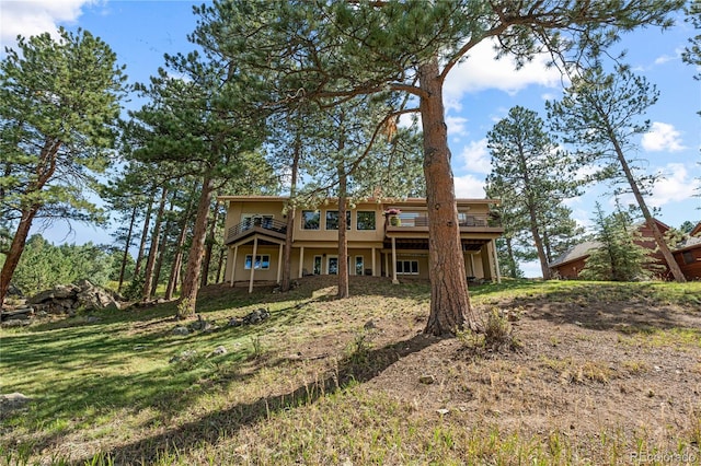back of property featuring a wooden deck, stucco siding, and a lawn