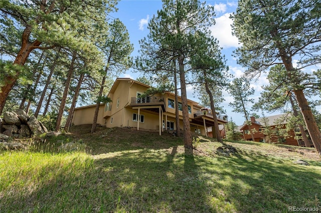 rear view of property with a deck, stucco siding, and a lawn