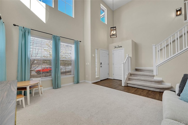 foyer entrance featuring a towering ceiling and dark carpet