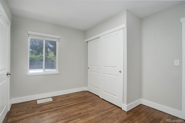 unfurnished bedroom featuring dark hardwood / wood-style flooring and a closet