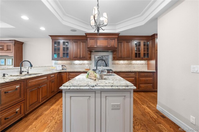 11 Canon Pl, Greenwood Village, CO 80111 - kitchen featuring a tray ceiling, light wood finished floors, a kitchen island, tasteful backsplash, and recessed lighting