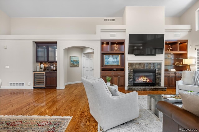 11 Canon Pl, Greenwood Village, CO 80111 - living room featuring wine cooler, wood finished floors, a glass covered fireplace, arched walkways, and bar